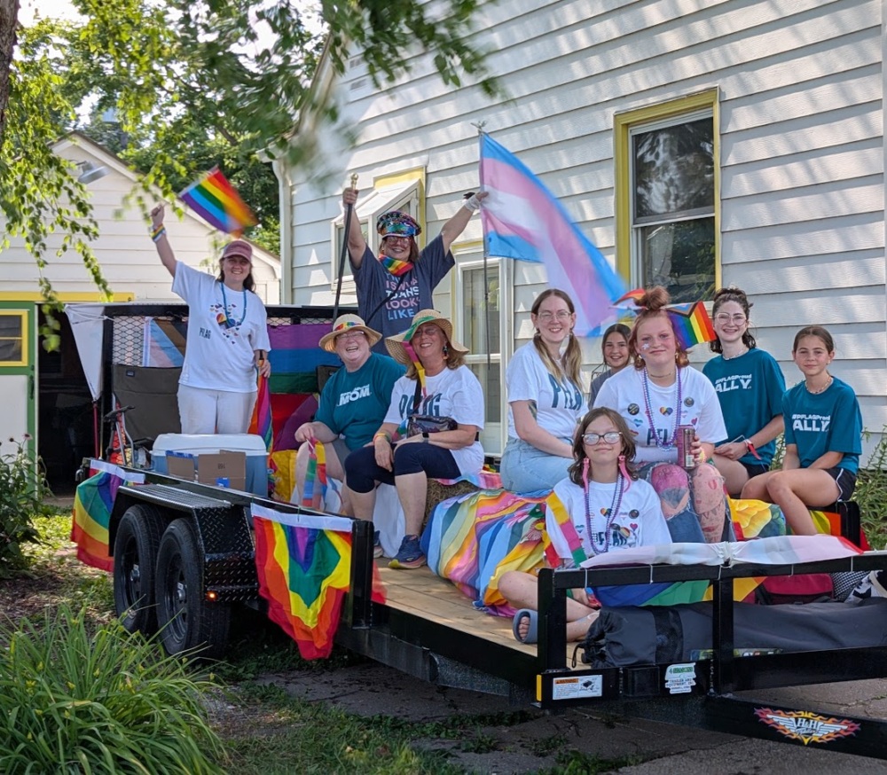 A group of people on a trailer decorated with pride flags